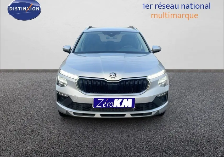 Vue frontale d'un Skoda Kamiq gris argent métal avec calandre noire et feux LED allumés sur fond neutre.