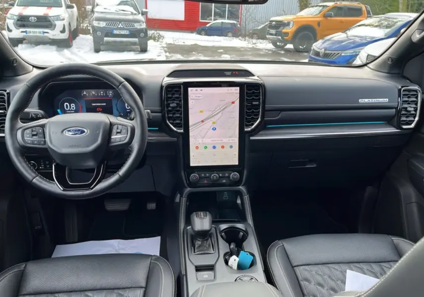 Vue intérieure avant du Ford Ranger 2026 Platinum avec tableau de bord noir, écran tactile vertical et volant cuir multifonctions.