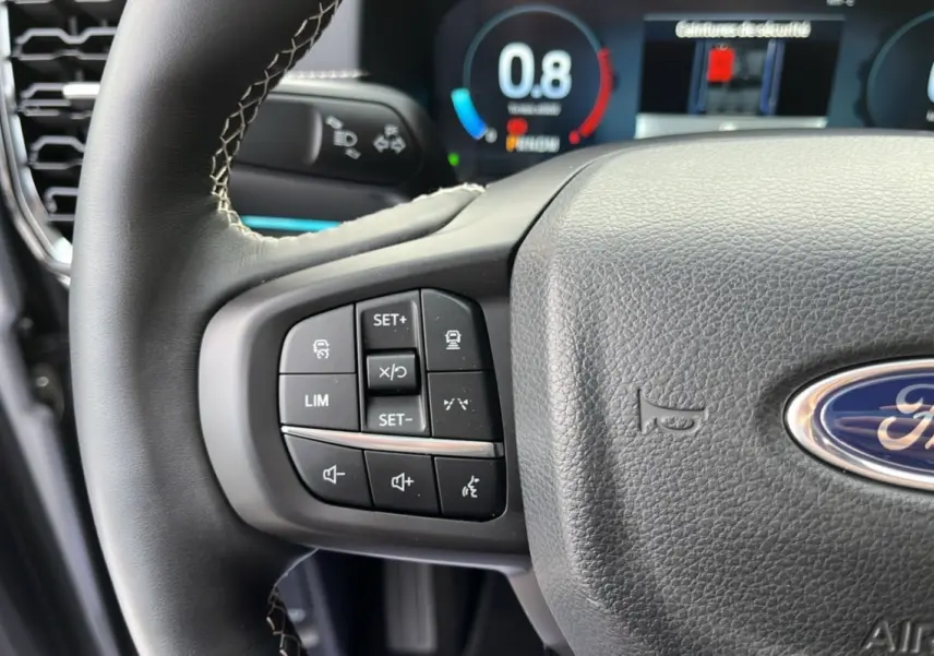 Gros plan sur le volant cuir multifonctions du Ford Ranger gris iconic, avec commandes de régulateur et affichage numérique en arrière-plan.