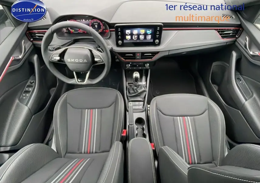 Vue intérieure avant du Skoda Kamiq blanc nacré 2026, sièges sport noirs avec bandes rouges et tableau de bord moderne.