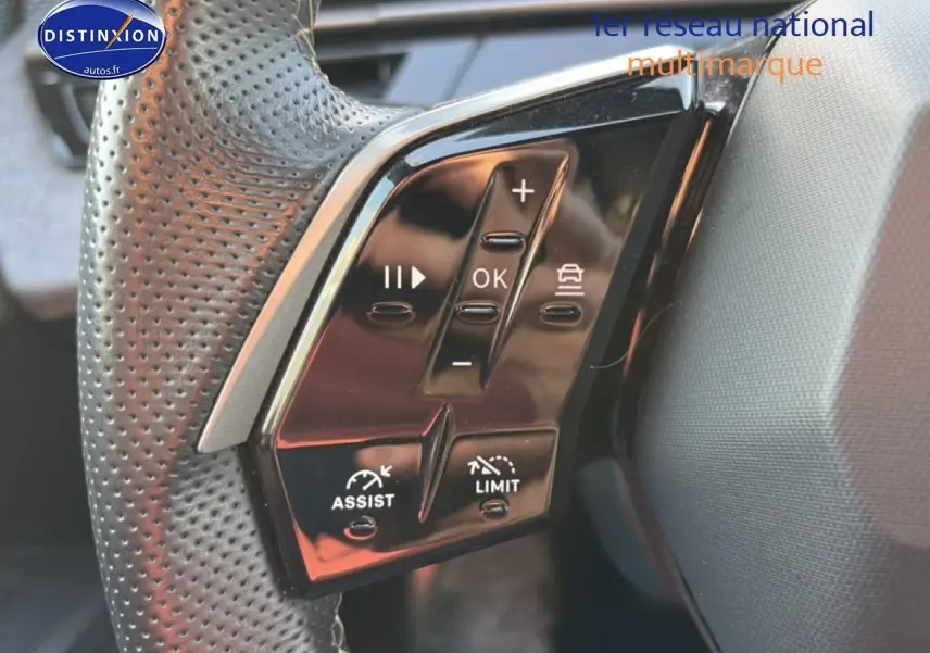 Gros plan sur les commandes multifonctions noires du volant cuir perforé du Peugeot 3008 gris 2025.