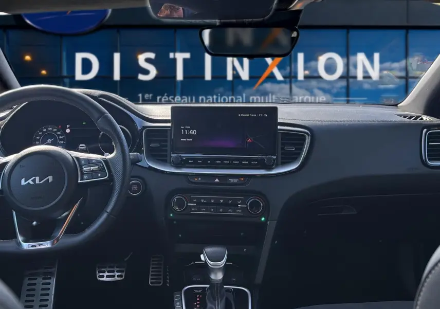 Vue intérieure avant du Kia Xceed gris 2024, tableau de bord avec écran tactile et volant multifonction cuir.