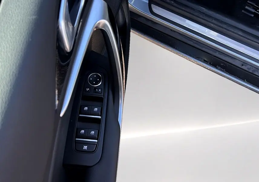 Gros plan sur la commande des vitres électriques côté conducteur d'une KIA Xceed gris 2024, avec poignée chromée.