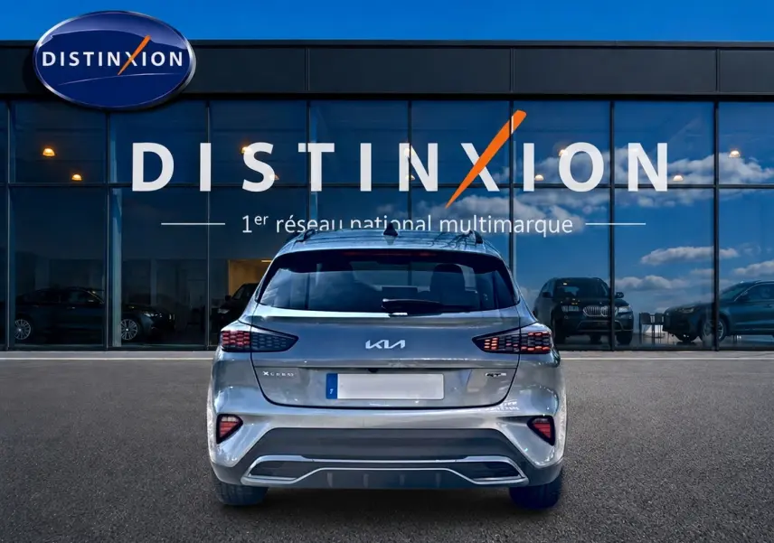Vue arrière d’un KIA Xceed gris 2024 GT-Line Premium avec feux LED et becquet, devant une vitrine Distinxion.