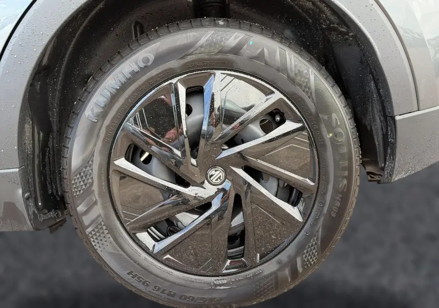 Gros plan sur la roue avant droite du MG ZS Camden grey, mettant en valeur la jante noire brillante au design moderne.