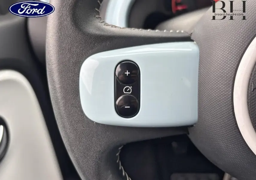 Gros plan sur les commandes de régulateur de vitesse sur le volant bleu dragée de la Renault Twingo 2014.