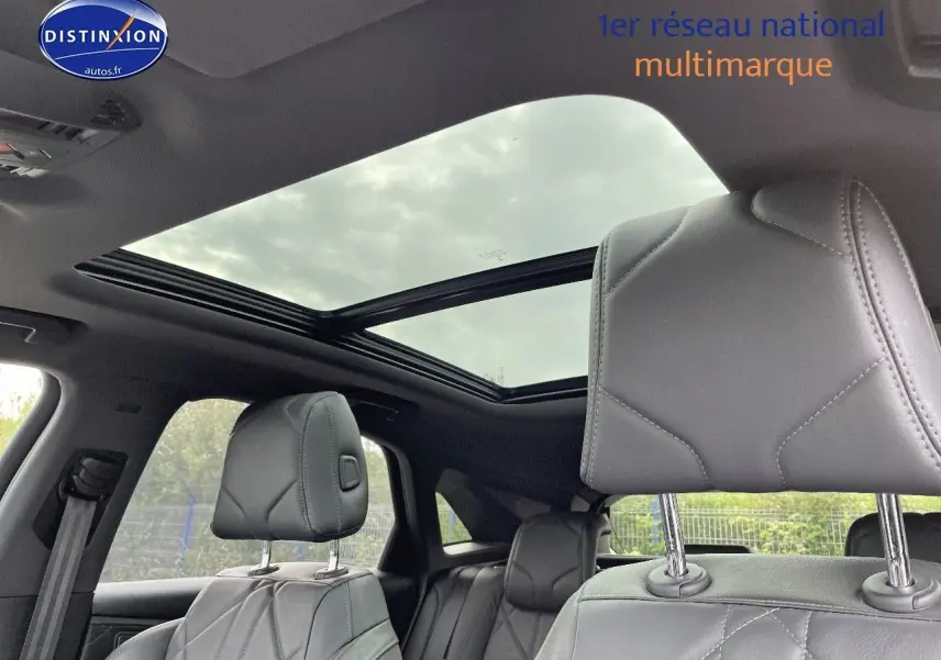 Intérieur du DS7 Crossback E-TENSE 2021 en cuir noir, vue sur les sièges avant et toit panoramique ouvert.