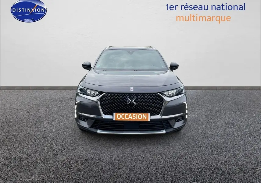 Vue frontale d'un DS7 Crossback gris platinium métal avec calandre distinctive et feux LED allumés.