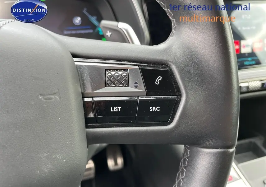 Gros plan sur les commandes au volant en cuir noir du DS7 Crossback E-TENSE 2021, avec tableau de bord digital en arrière-plan.