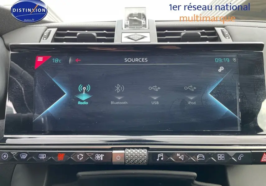 Écran tactile central du DS7 Crossback gris platinium, affichant les sources audio avec horloge et commandes tactiles.