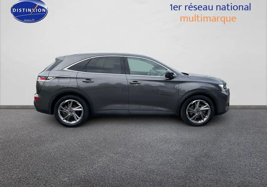 Vue latérale droite du DS7 Crossback gris platinium métallisé, SUV hybride rechargeable élégant stationné sur sol gris.