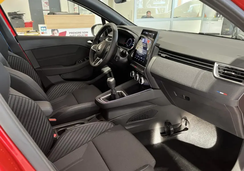 Intérieur avant de la Renault Clio 1.0 Tce 90 Esprit Alpine 2024 rouge, avec sièges noirs et console centrale moderne.