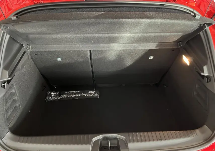 Coffre ouvert de la Renault Clio rouge 2024, montrant un espace de rangement propre avec kit de sécurité noir.