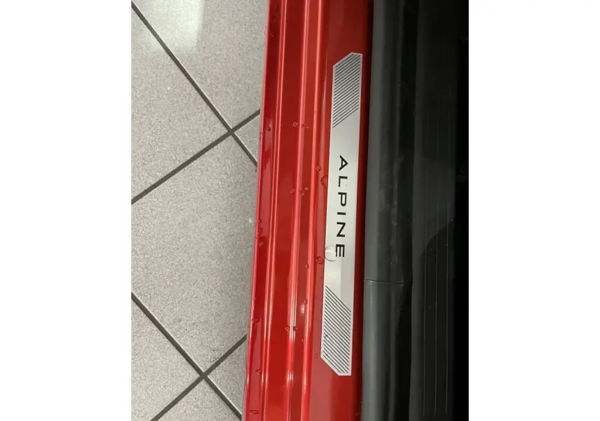Gros plan sur la plaque de seuil de porte rouge de la Renault Clio 2024 version Esprit Alpine avec logo Alpine.