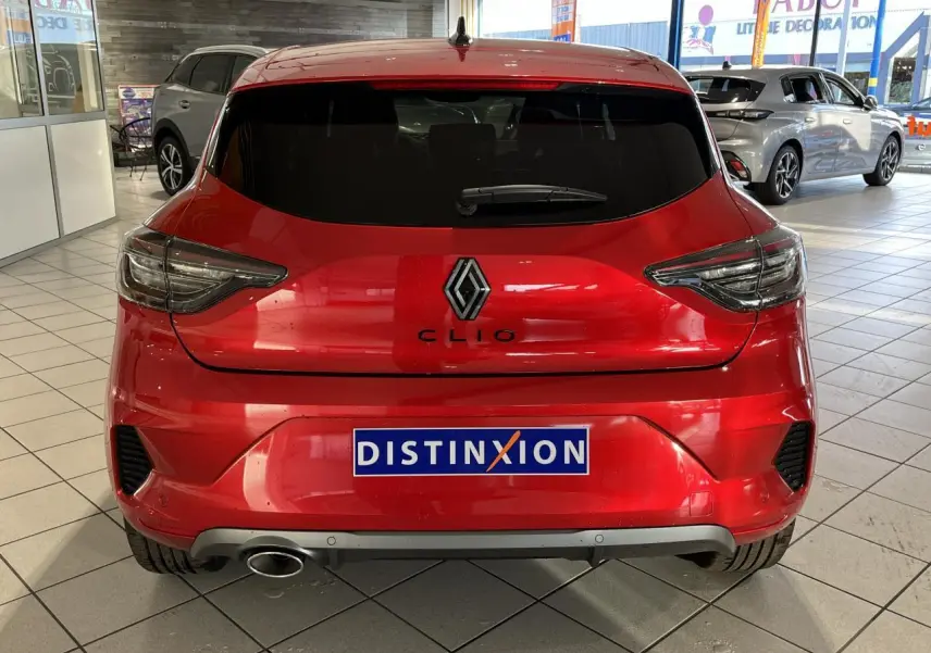 Vue arrière d'une Renault Clio rouge 2024 avec logo et échappement chromé en concession.