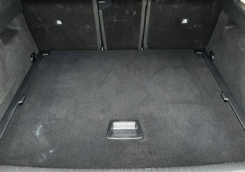 Vue intérieure du coffre fermé du Peugeot 3008 III Hybrid 145 Allure, revêtement noir et espace de rangement plat.