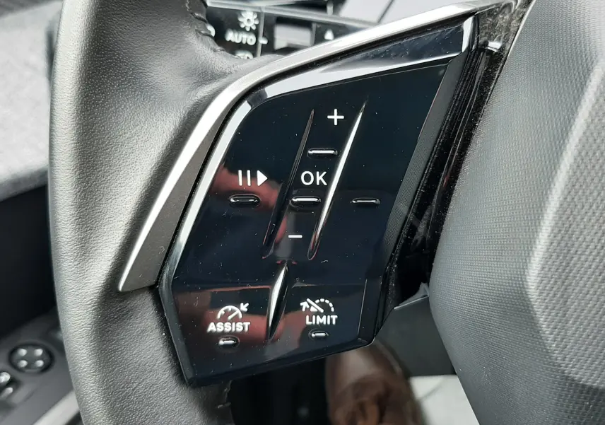 Gros plan sur les commandes noires du volant côté gauche du Peugeot 3008 III Hybrid 145 Allure bleu Ingaro.