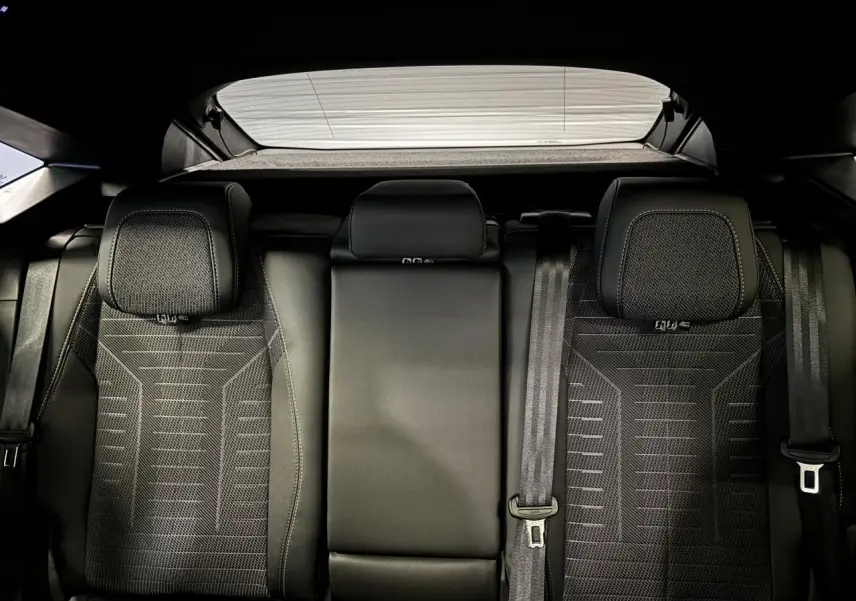 Vue arrière des sièges arrière noirs du Peugeot 3008 Hybrid 2025, avec appuie-têtes et ceintures visibles.