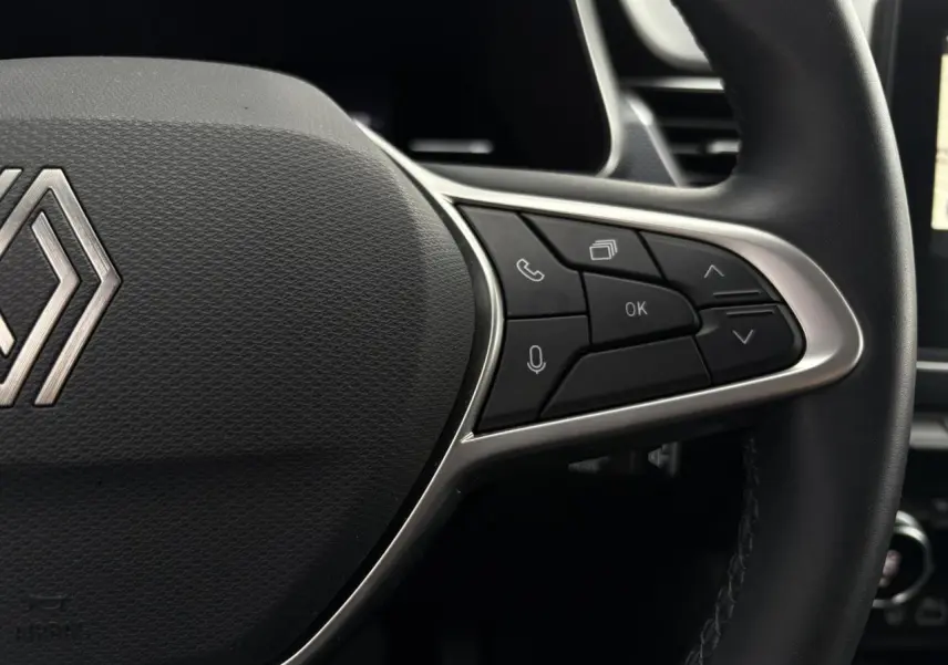 Gros plan sur le volant noir de la Renault Arkana 2025 avec commandes multifonctions et logo central argenté.
