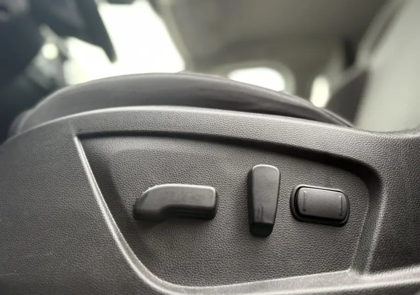 Gros plan sur les commandes électriques de réglage du siège conducteur du Renault Arkana TCE 140 bleu Zanzibar 2025.