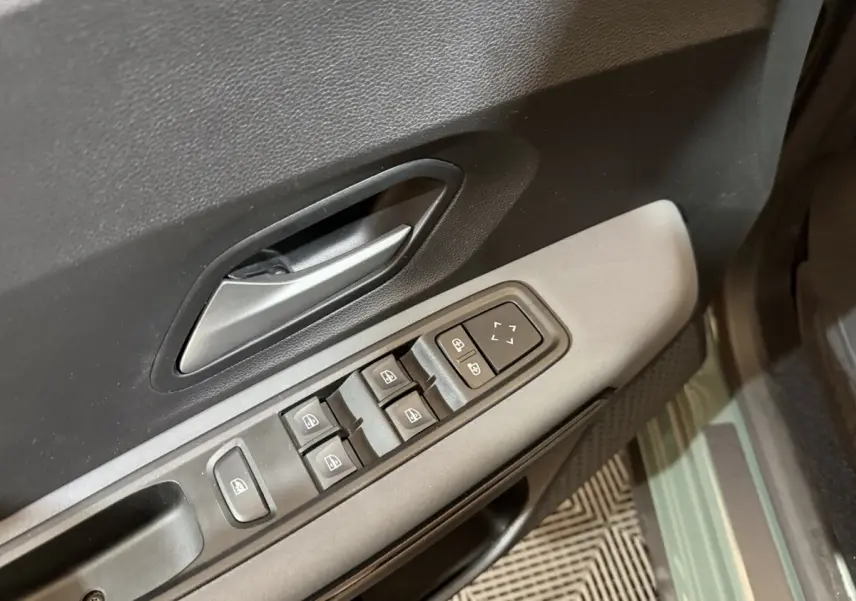 Gros plan sur la commande des vitres côté conducteur de la Dacia Sandero Extreme+ TCe 110 verte, porte ouverte.
