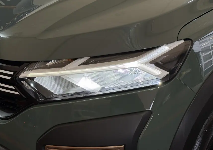Gros plan sur le phare avant droit LED d'une Dacia Sandero Extreme+ TCe 110 2024 vert foncé avec calandre noire.