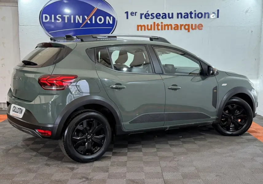 Vue latérale droite d'une Dacia Sandero Extreme+ TCe 110 2024 vert mat avec jantes noires et barres de toit assorties.