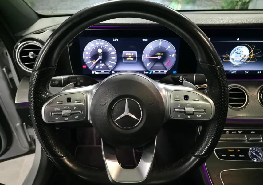 Vue rapprochée du volant en cuir noir et du tableau de bord numérique éclairé d’une Mercedes Classe E Break AMG Line 2020.