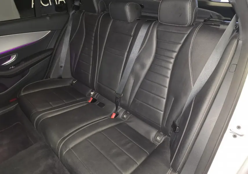 Vue côté droit de la banquette arrière en cuir noir avec surpiqûres blanches et éclairage d’ambiance violet d’une Mercedes Classe E Break 2020.
