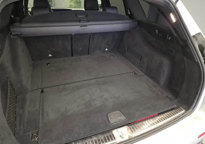 Coffre ouvert d'un break Mercedes Classe E gris, vue arrière montrant l'espace de chargement et la banquette rabattue.