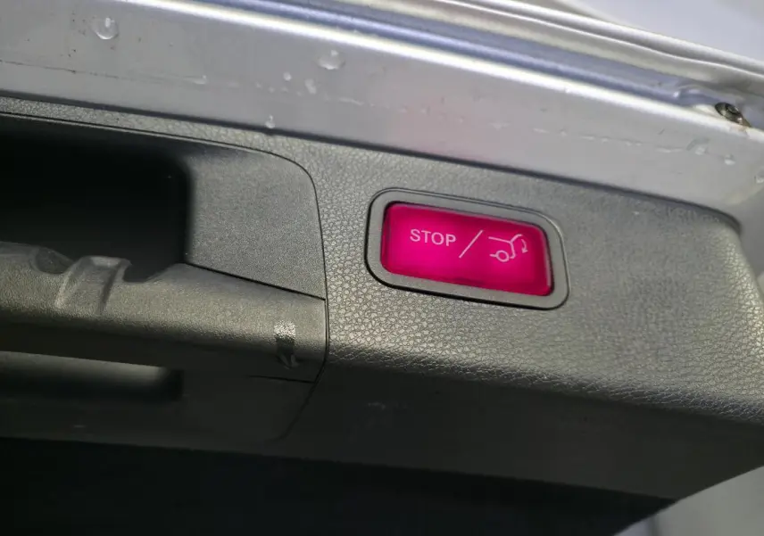 Bouton rouge STOP pour fermeture électrique du hayon sur le bord intérieur du coffre d’un Mercedes Classe E Break gris.
