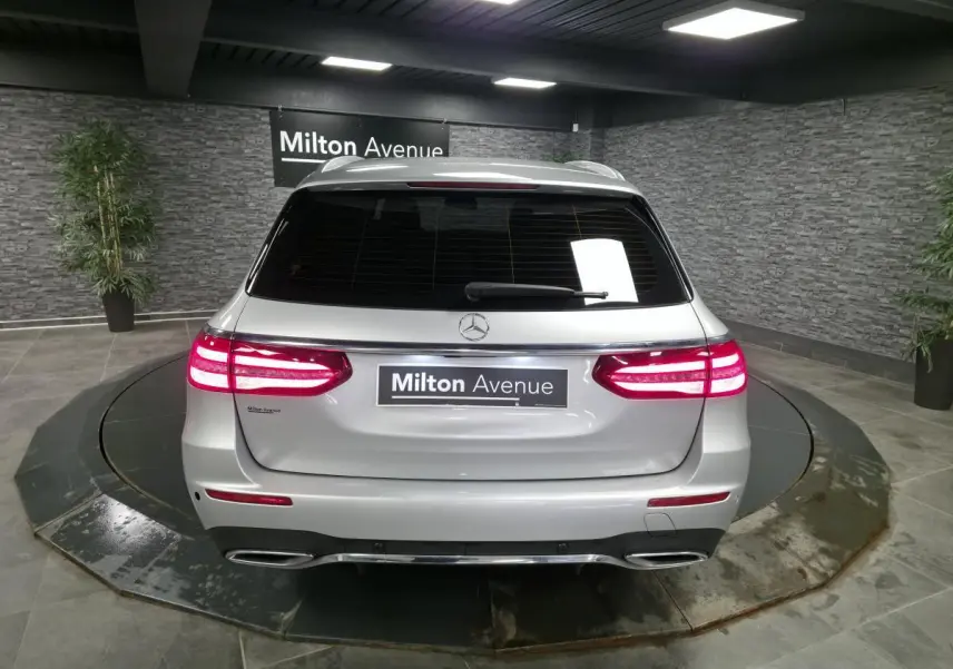 Vue arrière d'un break Mercedes Classe E gris métallisé avec feux LED allumés dans un showroom.