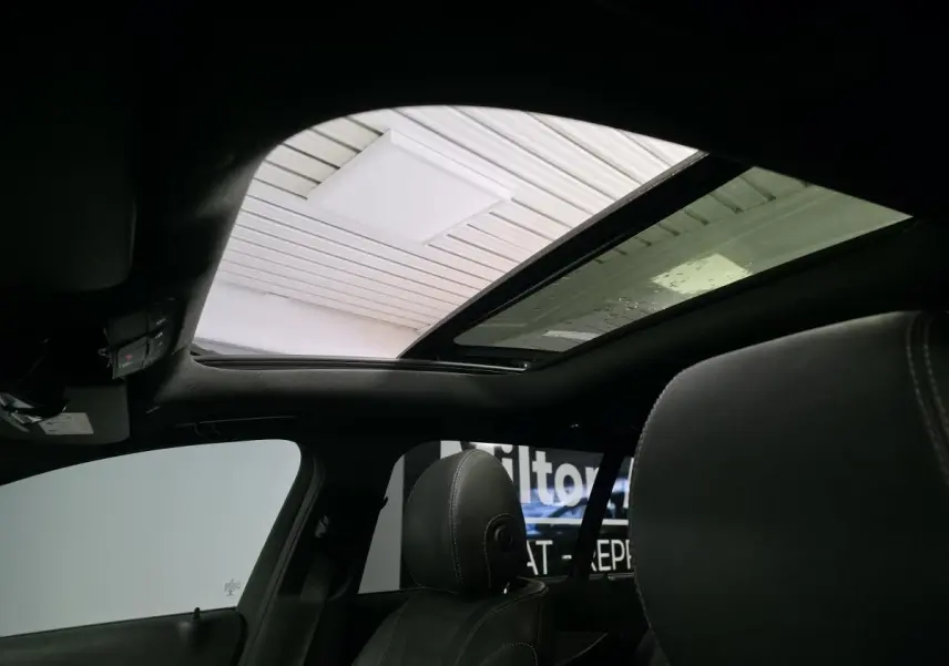 Vue intérieure du toit ouvrant panoramique en verre d'une Mercedes Classe E Break gris, avec sièges avant en cuir noir.