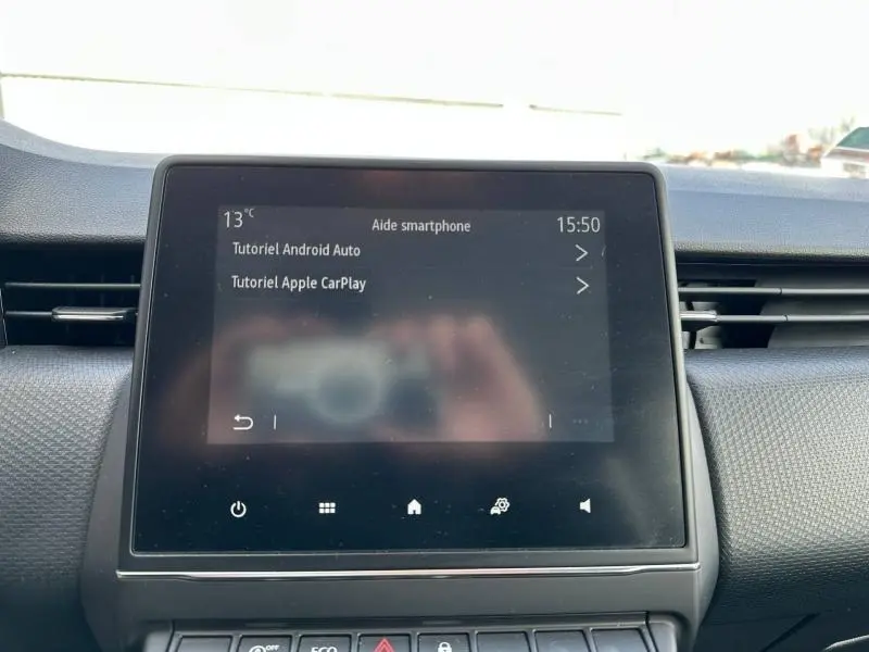 Écran tactile central du tableau de bord de la Renault Clio 2023, affichant les tutoriels Android Auto et Apple CarPlay.