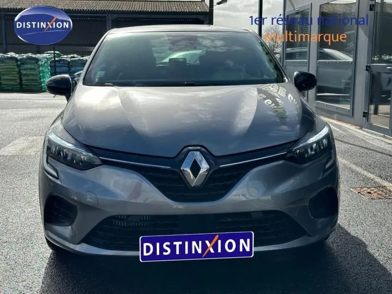 Vue avant d'une Renault Clio gris 2023 avec logo distinctif et calandre noire brillante, stationnée en extérieur.