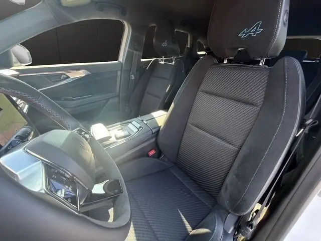 Vue intérieure côté conducteur du Renault Austral Esprit Alpine blanc, sièges noirs avec logo Alpine brodé sur appuie-tête.