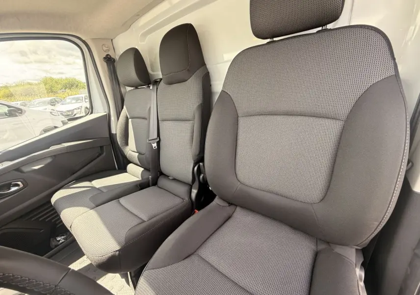 Vue intérieure avant droite sur les sièges gris du Renault Trafic Fourgon blanc, version 2025, avec ceinture de sécurité visible.