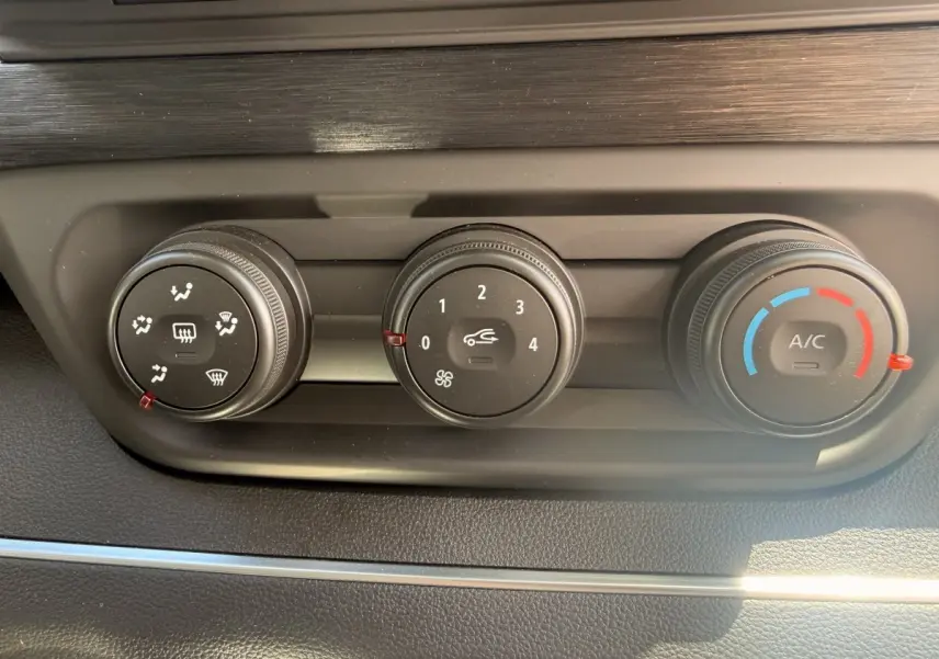 Gros plan sur les commandes de climatisation du Renault Trafic Fourgon blanc, avec réglages de ventilation, air recyclé et température.