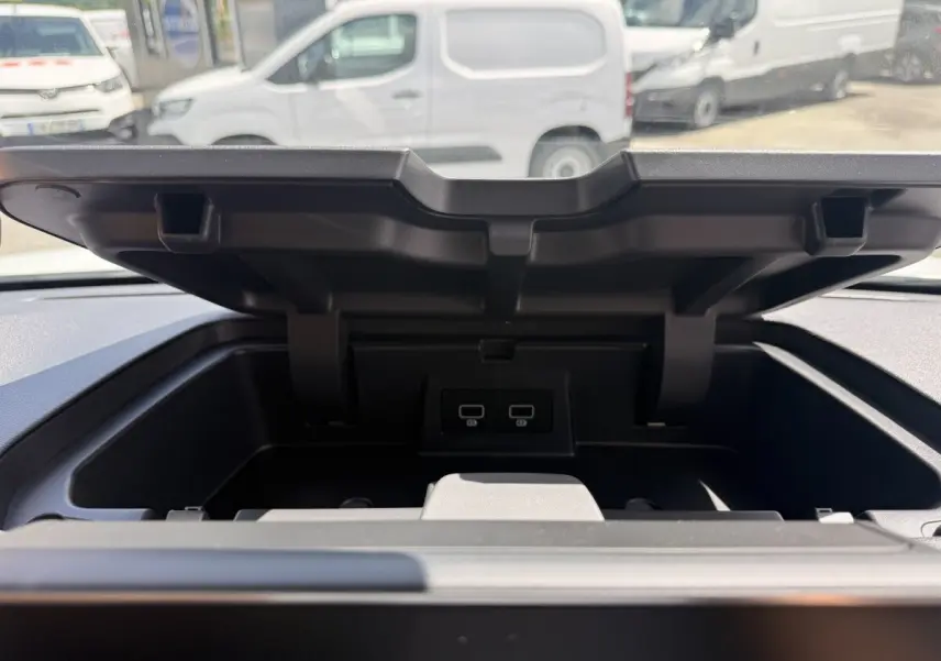 Vue rapprochée du compartiment de rangement ouvert sur le tableau de bord du Renault Trafic Fourgon blanc.