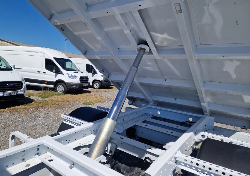 Vue rapprochée de la benne blanche relevée du Renault Master Châssis Cabine 2024, avec vérin hydraulique apparent.