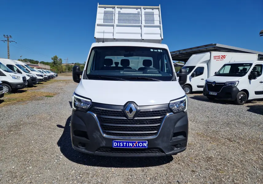 Vue frontale d’un Renault Master Châssis Cabine blanc avec benne sur un parking en extérieur sous ciel bleu.