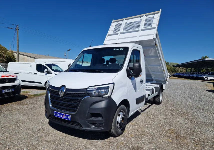 Renault Master Benne blanche vue 3/4 avant droit avec benne relevée et roues jumelées sur parking extérieur.