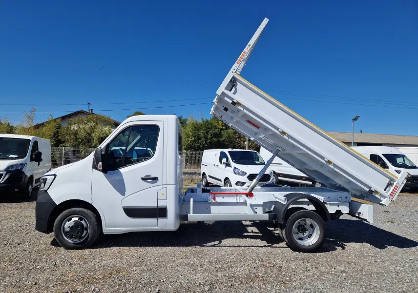 Profil droit du Renault Master Châssis Cabine blanc 2024 avec benne relevée et roues jumelées visibles.