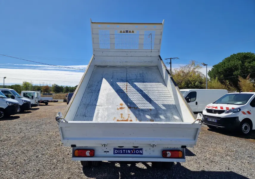 Vue arrière en contre-plongée d’un Renault Master Châssis Cabine blanc avec benne basculée et plateau métallique usé.