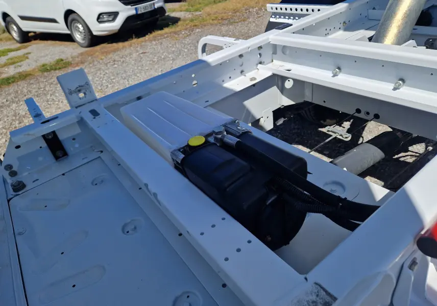 Vue rapprochée du châssis blanc du Renault Master Benne L2, montrant la structure métallique et un réservoir noir intégré.