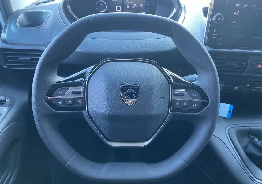 Vue rapprochée du volant noir du Peugeot Partner 2024 avec tableau de bord numérique et écran tactile visible.