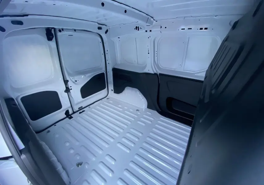 Intérieur du coffre blanc du Peugeot Partner 2024, vue plongeante montrant l’espace de chargement vide et les parois métalliques.