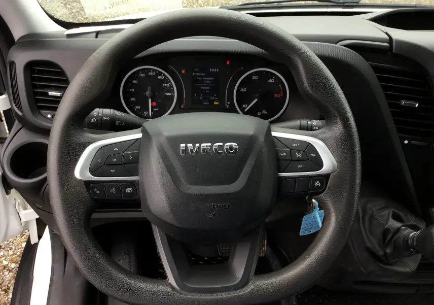 Vue rapprochée du volant Iveco avec commandes intégrées et tableau de bord digital du Daily Chassis Double Cabine blanc.
