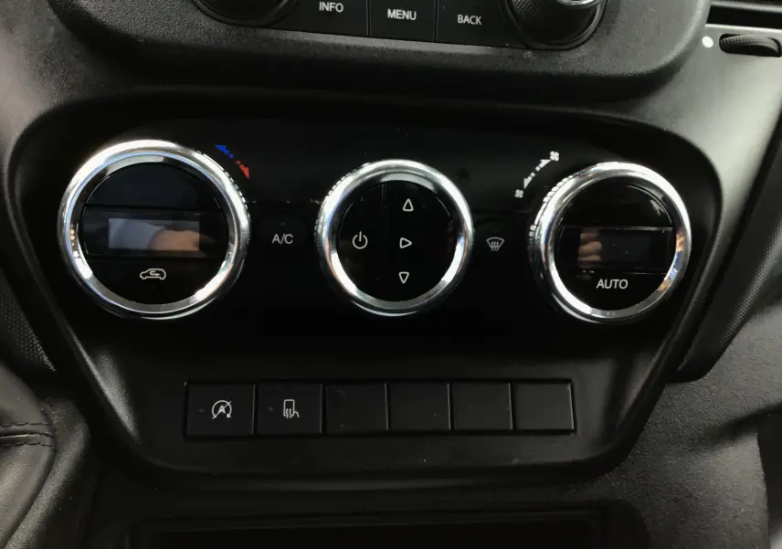 Gros plan sur les commandes de climatisation automatique du tableau de bord noir de l'Iveco Daily Chassis double cabine blanc.