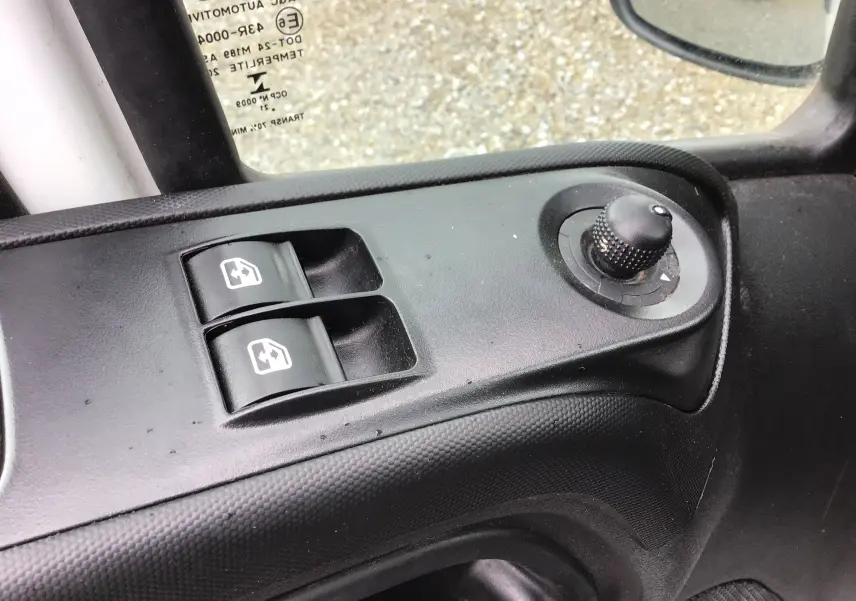 Gros plan sur les commandes de lève-vitres et réglage des rétroviseurs côté conducteur d'un Iveco Daily blanc de 2021.